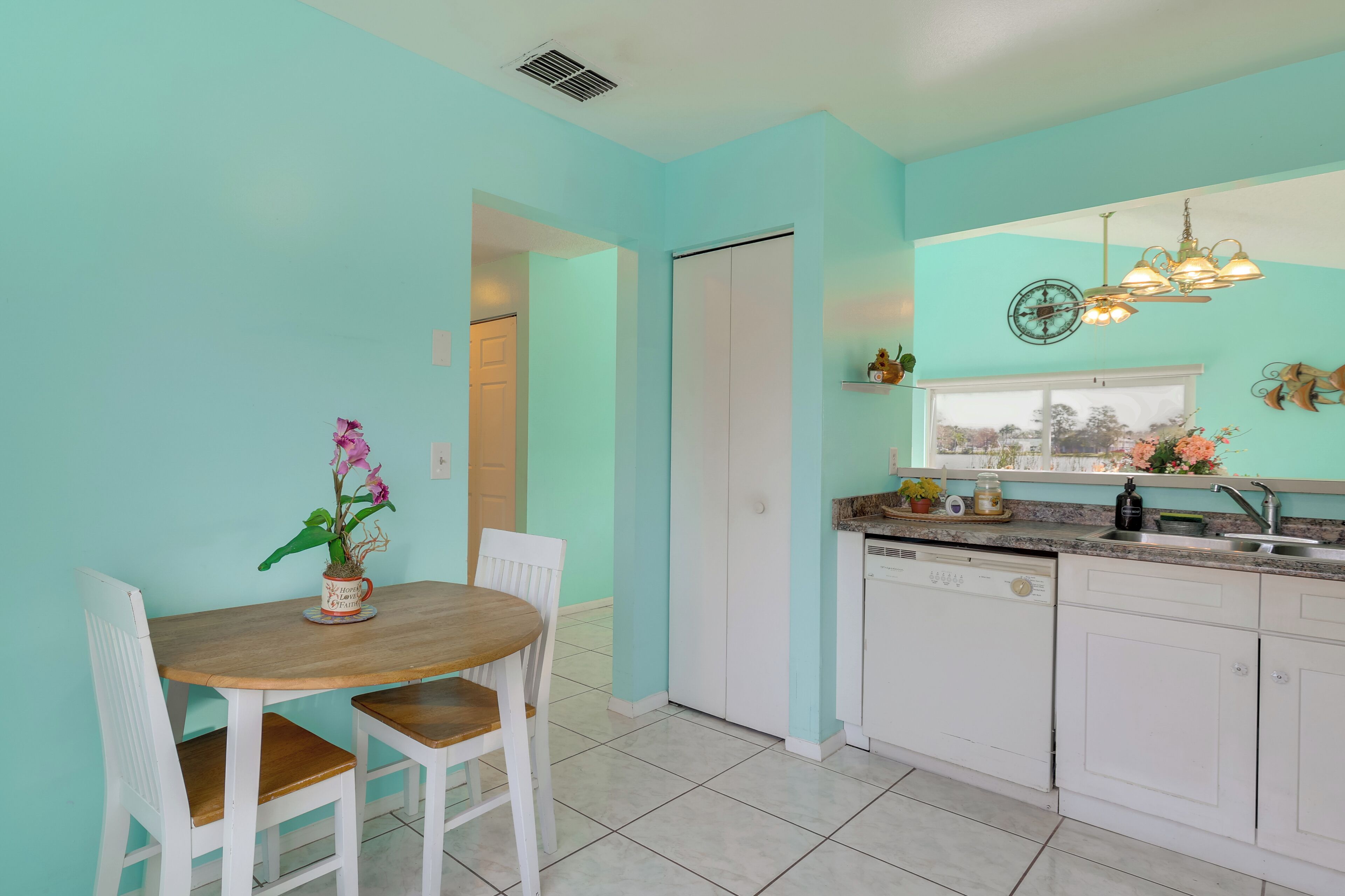 A kitchen with white cabinets, a dishwasher, and a window with a view.