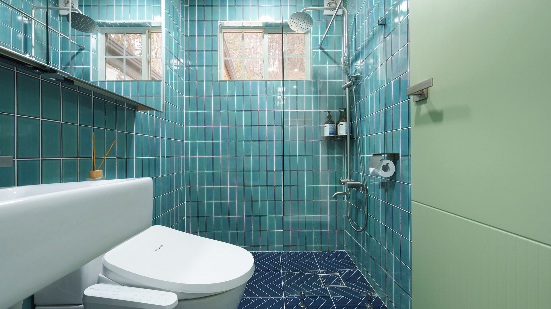 A bathroom with a toilet, a shower, and a window.