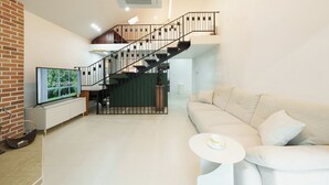 A modern living room with a staircase, a television, a sofa, and a small table. - Gapyeong Hotel Forest Hue Pension (Gapyeong)