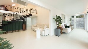 A modern living room with a staircase, a sofa, a coffee table, and a large plant. - Gapyeong Hotel Forest Hue Pension (Gapyeong)