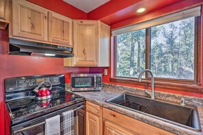 A kitchen with wooden cabinets, a stove, a microwave, and a sink. - Secluded Mtn Escape! Cabin 6 Mi to Mueller Park (Divide)