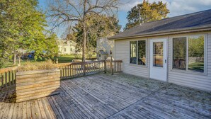 A wooden deck with a wooden planter, a white house with a garage, and a clear sky. - Angler's Retreat 1 Block to Lake Winneconne (Winneconne)