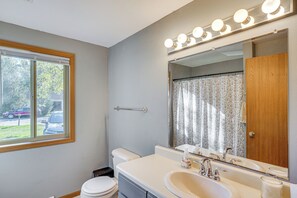 Une salle de bain avec des toilettes, un lavabo et un miroir.