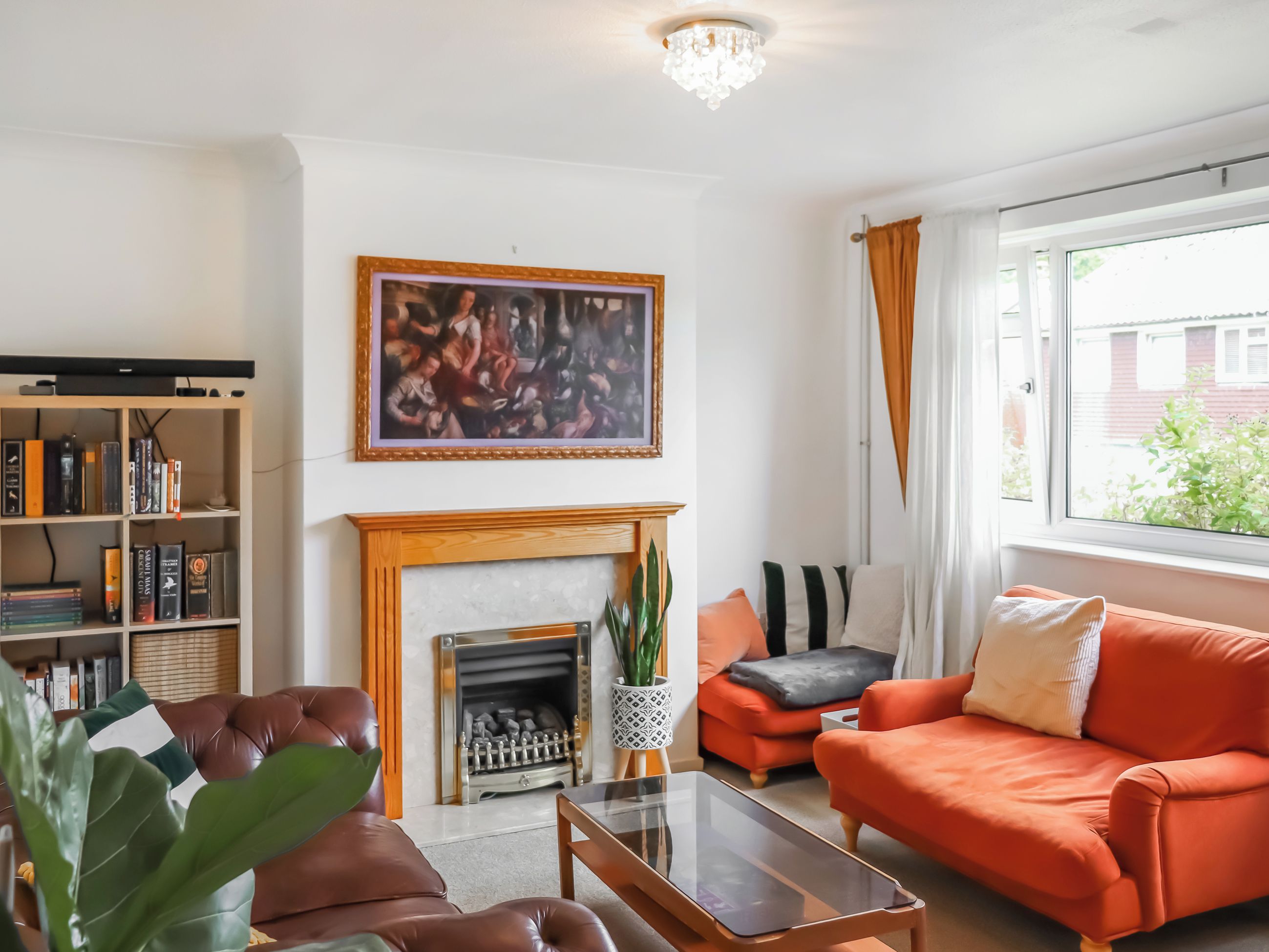 A living room with a fireplace, a bookshelf, a sofa, and a window with curtains.