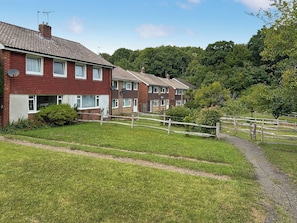 A row of terraced houses with a grassy front yard and a wooden fence. - 3 bedroom accommodation in Uckfield (Uckfield)