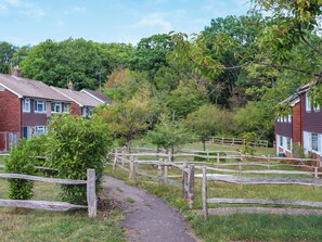 A rural pathway leading to a residential area with houses and a wooden fence. - 3 bedroom accommodation in Uckfield (Uckfield)