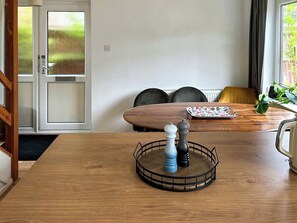 A dining area with a wooden table, a tray with a floral plate, and two salt and pepper shakers.
