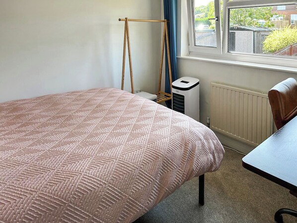 Une chambre à coucher avec un lit, une chaise, un radiateur et une fenêtre donnant sur l’extérieur.