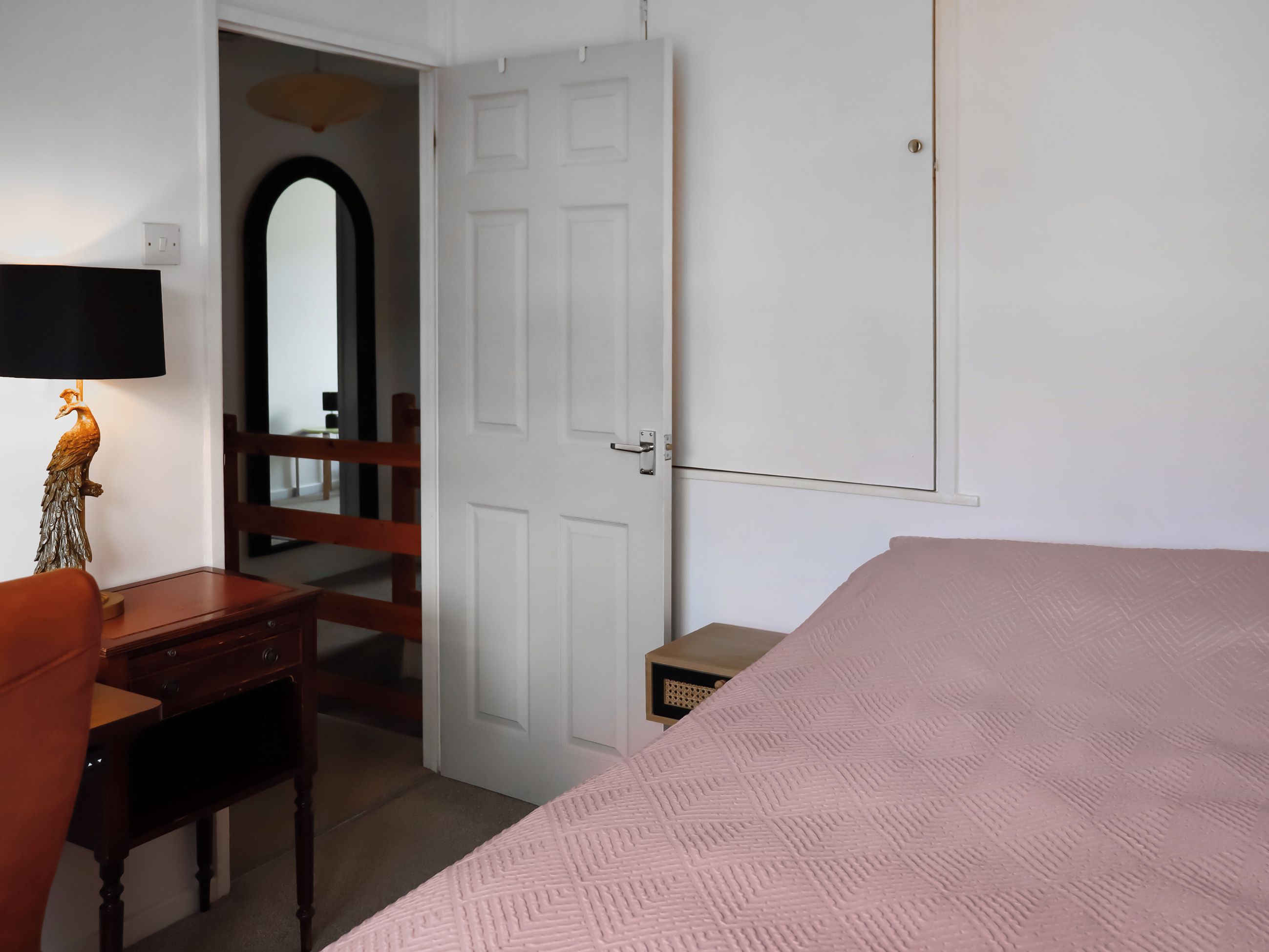 Une chambre à coucher avec un lit, un bureau avec une lampe, une porte et un miroir.