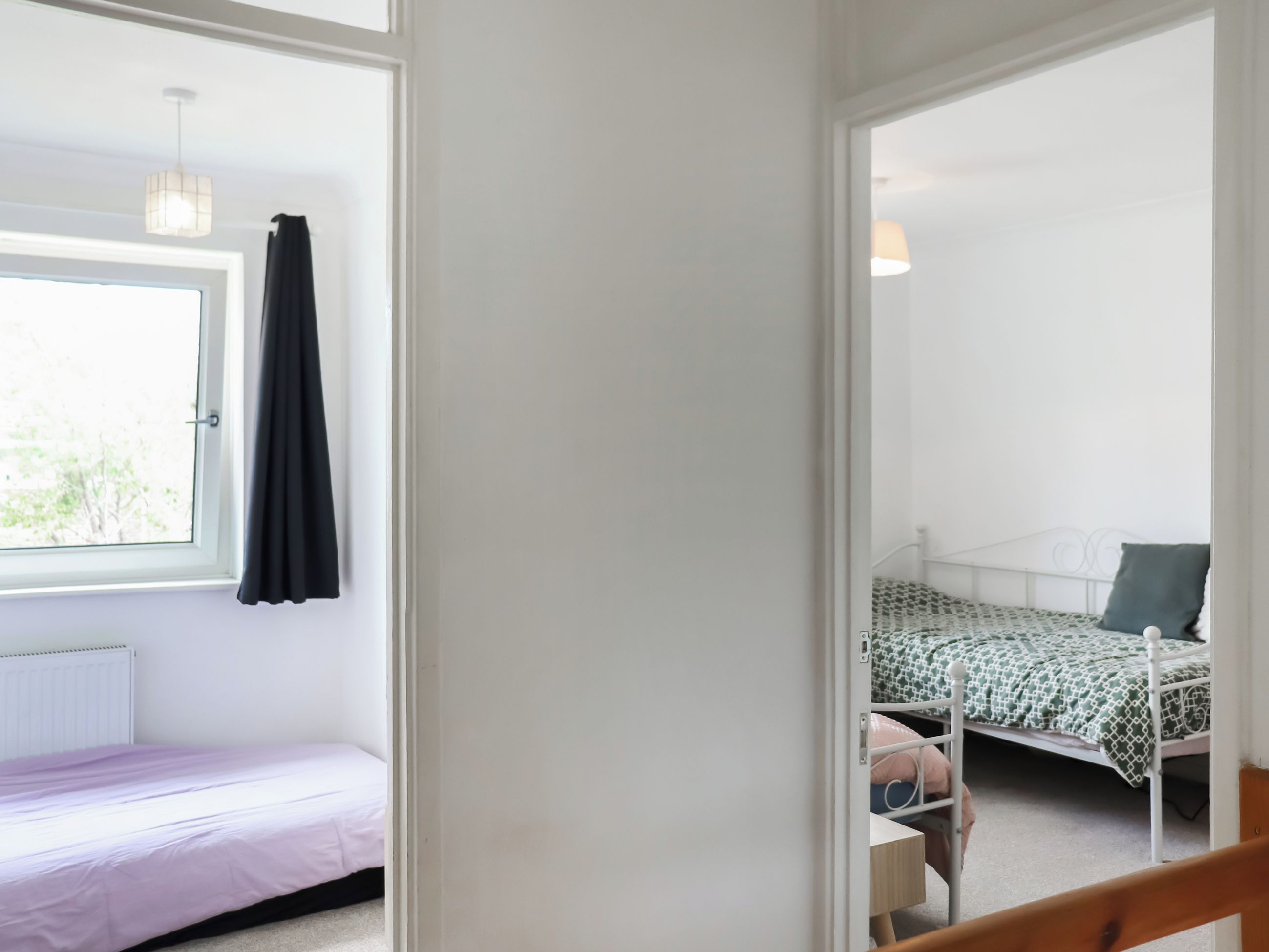 Een slaapkamer met een raam, een bed, een nachtkastje en een stoel.