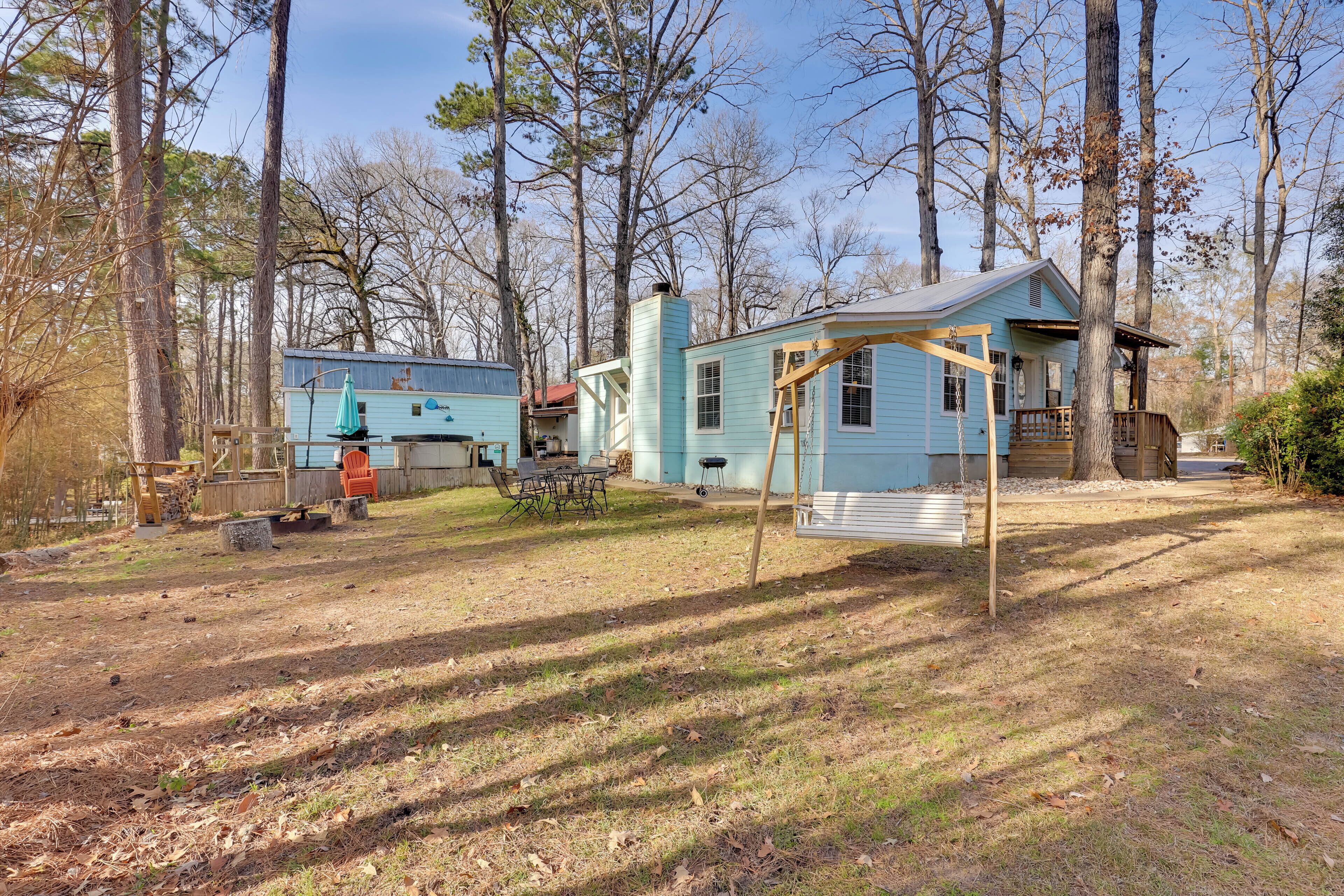 Une cabane rustique dotée d’un porche, entourée d’arbres.