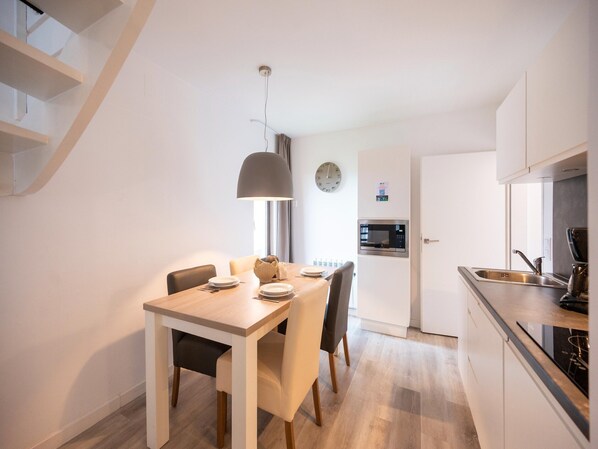 A modern kitchen with a built-in microwave, a dining area with a table and chairs, and a staircase leading to an upper level. - Nature Stay in Hambachtal Holiday Park (Oberhambach)