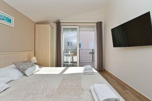 A hotel room with a bed, a TV, a balcony, and a view of the outside. - Holiday apartment with air conditioning and outdoor pool (Fažana)