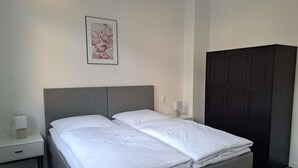 A bedroom with a double bed, a bedside table with a lamp, a wardrobe, and a framed picture on the wall. - Modern, spacious 3-room apartment - 85 m² (Solingen)