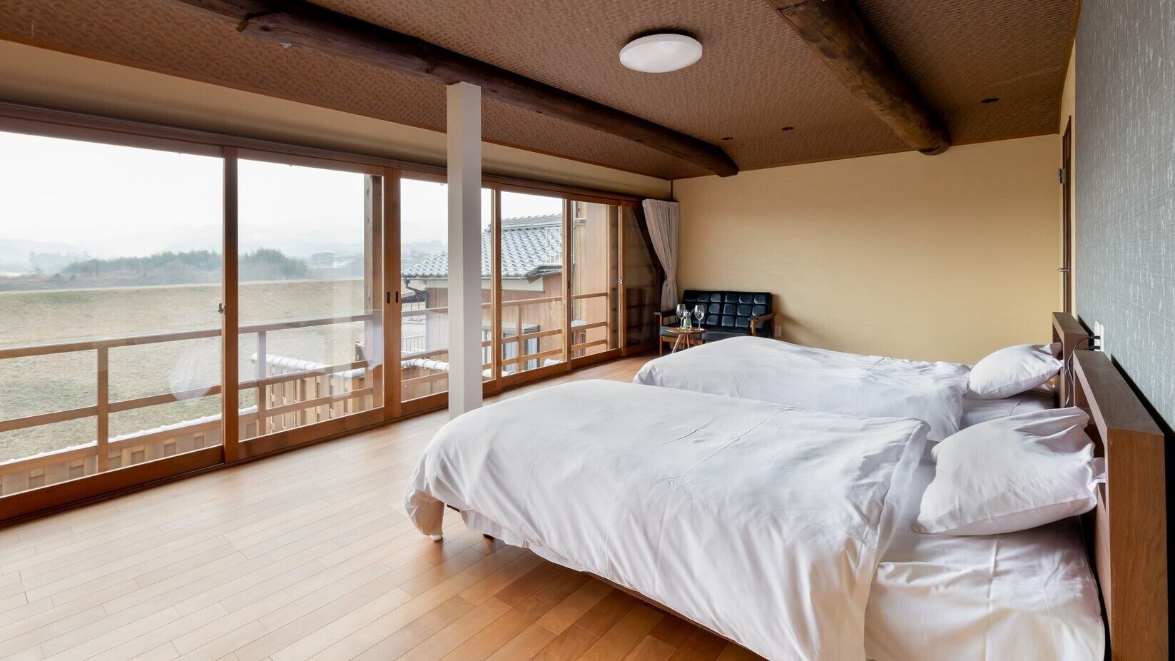 Una habitación con dos camas, ventanas amplias, vistas al río y suelo de madera.