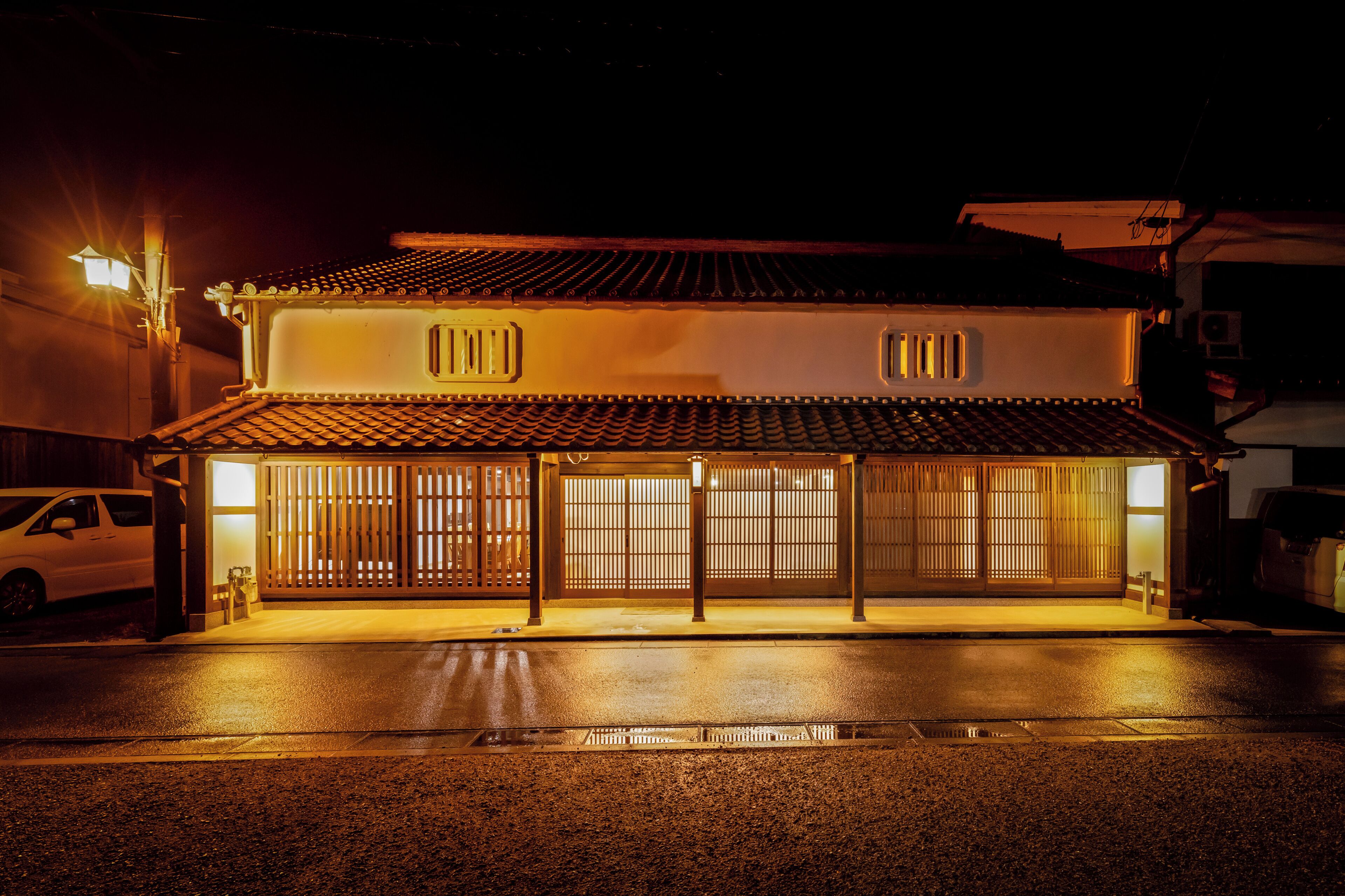 A traditional building with a tiled roof, a wooden gate, and a car parked in front.