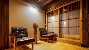 A traditional Japanese room with tatami flooring, two leather chairs, a bamboo brush, and a sliding glass door with shoji screens. - Oyado Satsuki Nara Gojo Shinmachi (Gojo)
