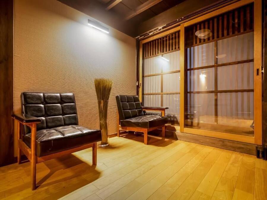 Et traditionelt japansk rum med tatami gulv, to læderstole, en bambusbørste og en skydedør med shoji skærme.