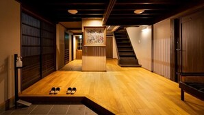A hallway with wooden flooring, a staircase, and a framed artwork on a pedestal. - Oyado Satsuki Nara Gojo Shinmachi (Gojo)