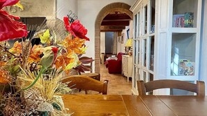 Ein Essbereich mit einem Holztisch und Stühlen, einer Blumenvase und einem Bücherregal mit Büchern.
