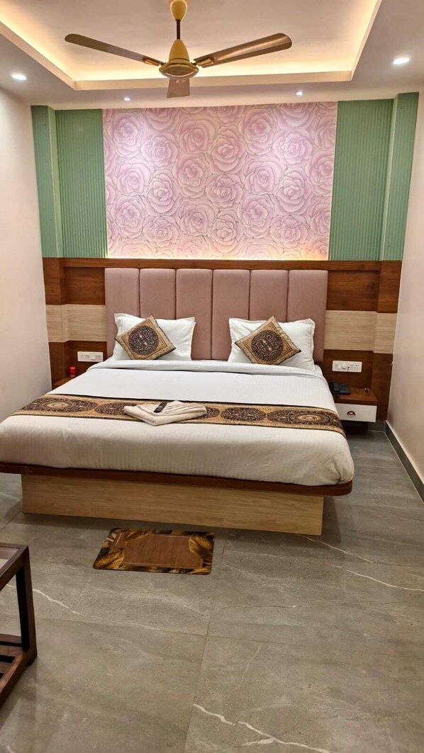 Une chambre à coucher avec un grand lit, un ventilateur de plafond, un mur décoratif et une table de chevet avec un téléphone.