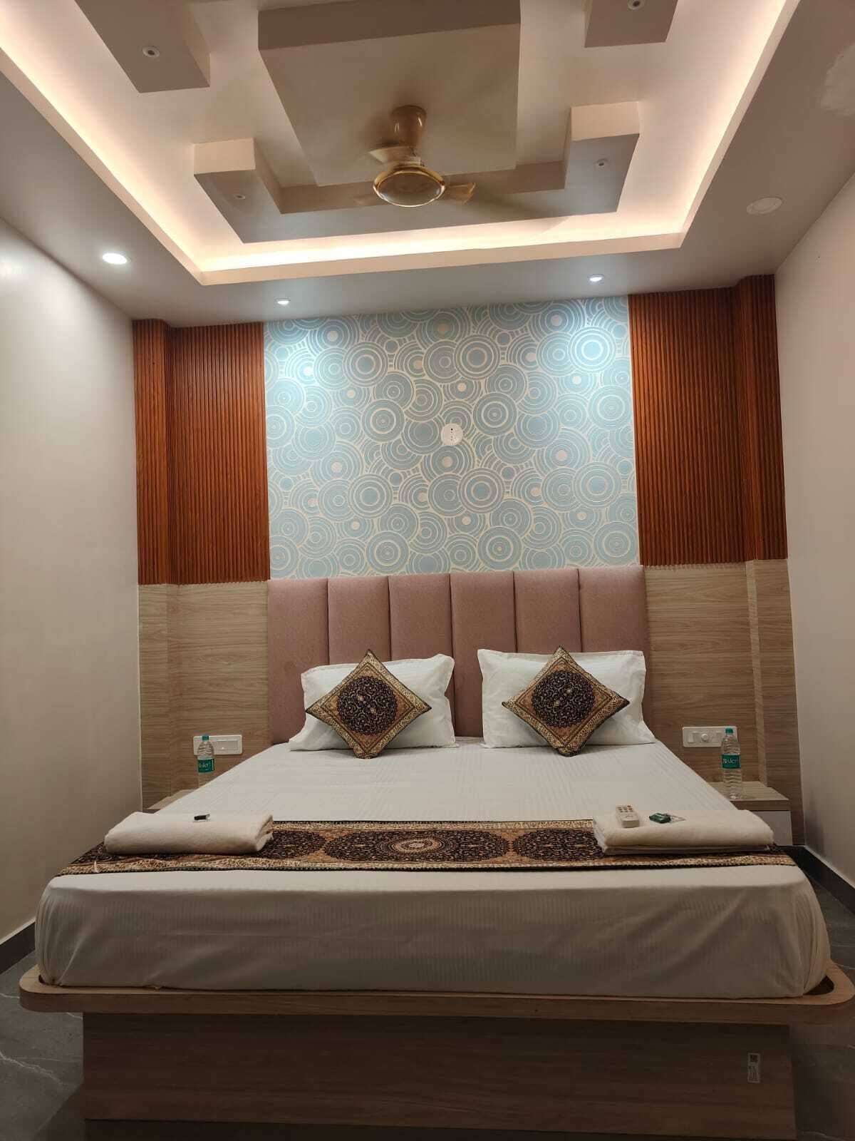 A modern bedroom with a large bed, a ceiling fan, and a patterned wall.