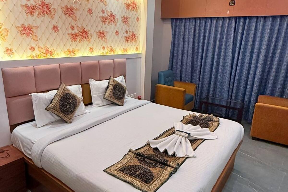 A modern hotel room with a large bed, a ceiling fan, and a decorative wall panel.