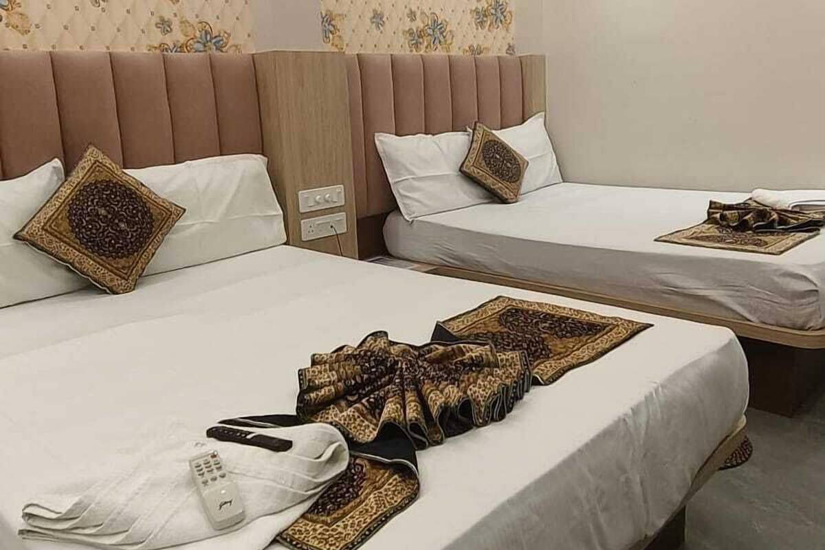 A hotel room with two beds, a ceiling fan, and a patterned wall.