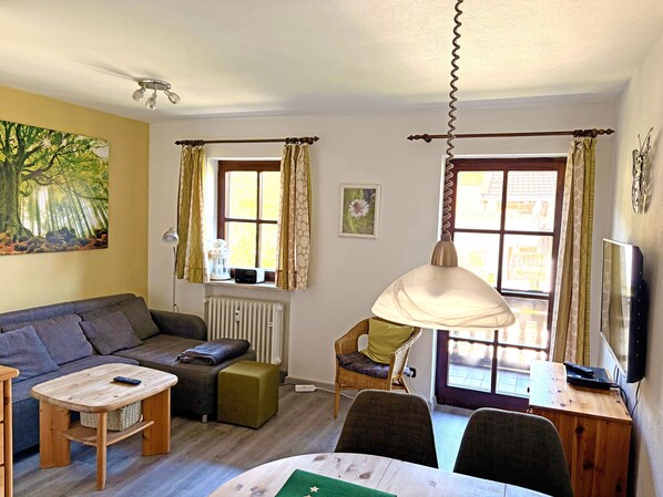 Un salon confortable avec un canapé, une petite table, un fauteuil, un radiateur et une fenêtre avec des rideaux.