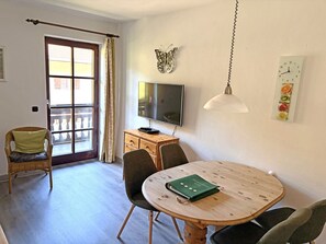 Une pièce comprenant une table à manger, des chaises, un téléviseur, une horloge et un élément de décoration représentant un papillon.