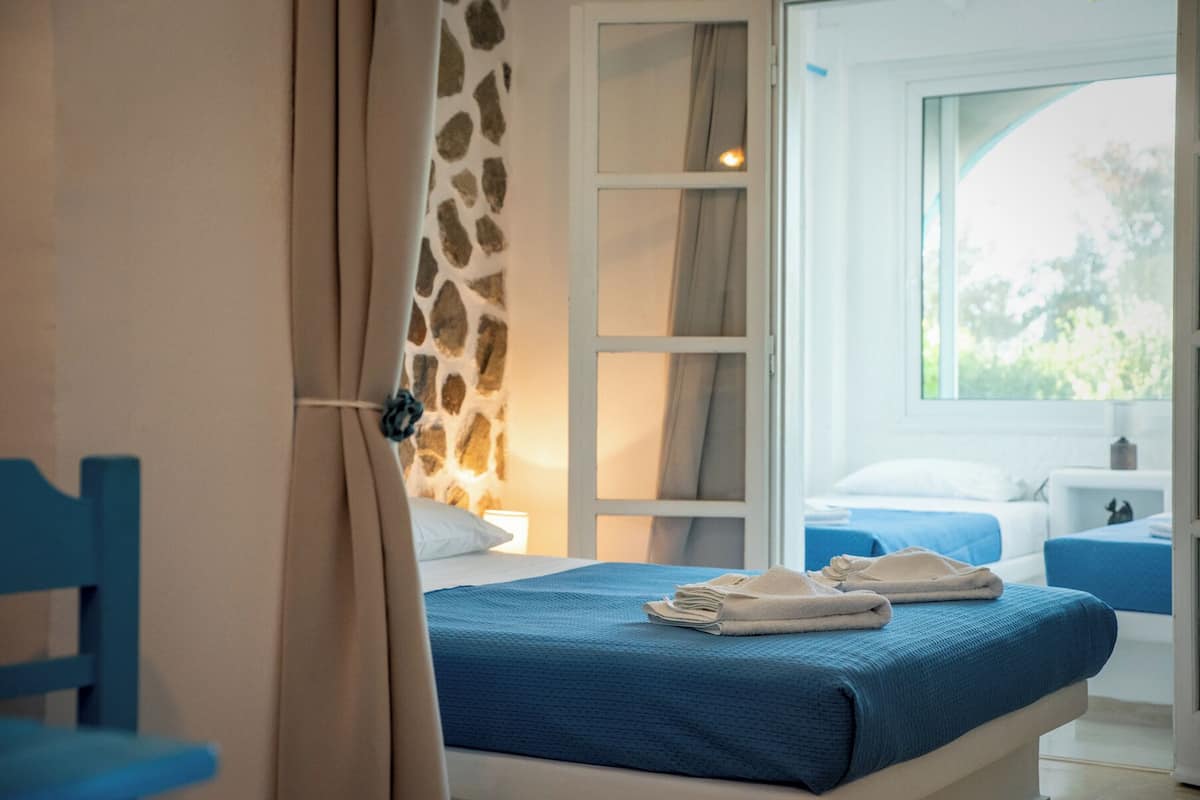 Une chambre à coucher avec un lit, une chaise et une fenêtre donnant sur un paysage verdoyant.