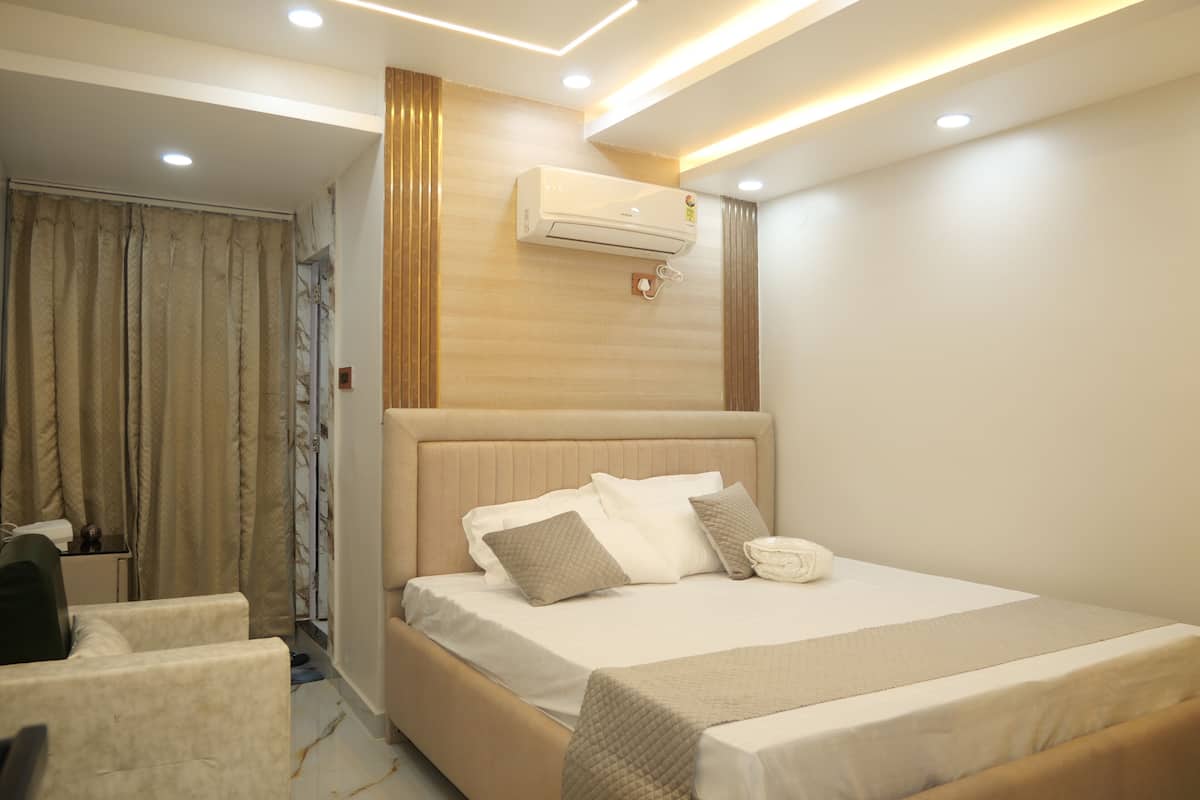 Un dormitorio moderno con una cama grande, una mesita de noche, un equipo de aire acondicionado y vistas a un baño con ducha y cortinas.