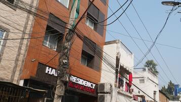 A building with a sign for 'HAPPY RESIDENCY' and 'DELUXE ACCTROOMS'.