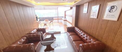 A lobby with leather sofas, a coffee table, and framed artwork on the walls.