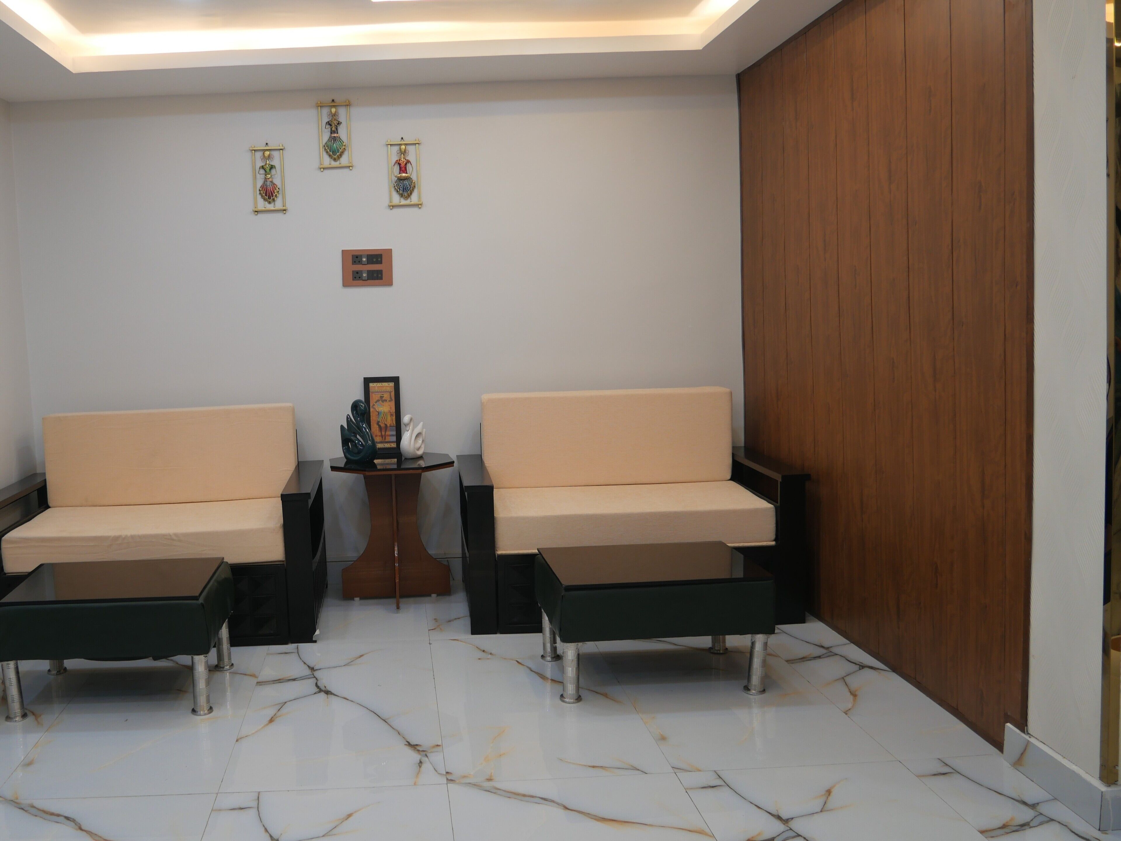 A modern waiting area with two sofas, a small table with decorative items, and a wooden panel on the wall.