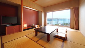 A traditional Japanese room with tatami flooring, a low table, a television, and a view of the sea. - tabiyadoyobuko (Karatsu)