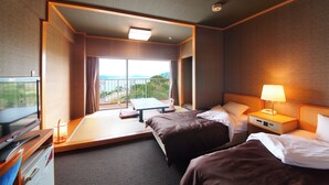 A hotel room with two beds, a desk with a computer, a TV, and a balcony with a view of the sea. - tabiyadoyobuko (Karatsu)