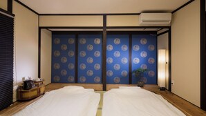 Ein traditioneller japanischer Raum mit Tatami-Boden, Futon-Bett, Shoji-Schirm und einem kleinen Tisch mit Wasserkocher.