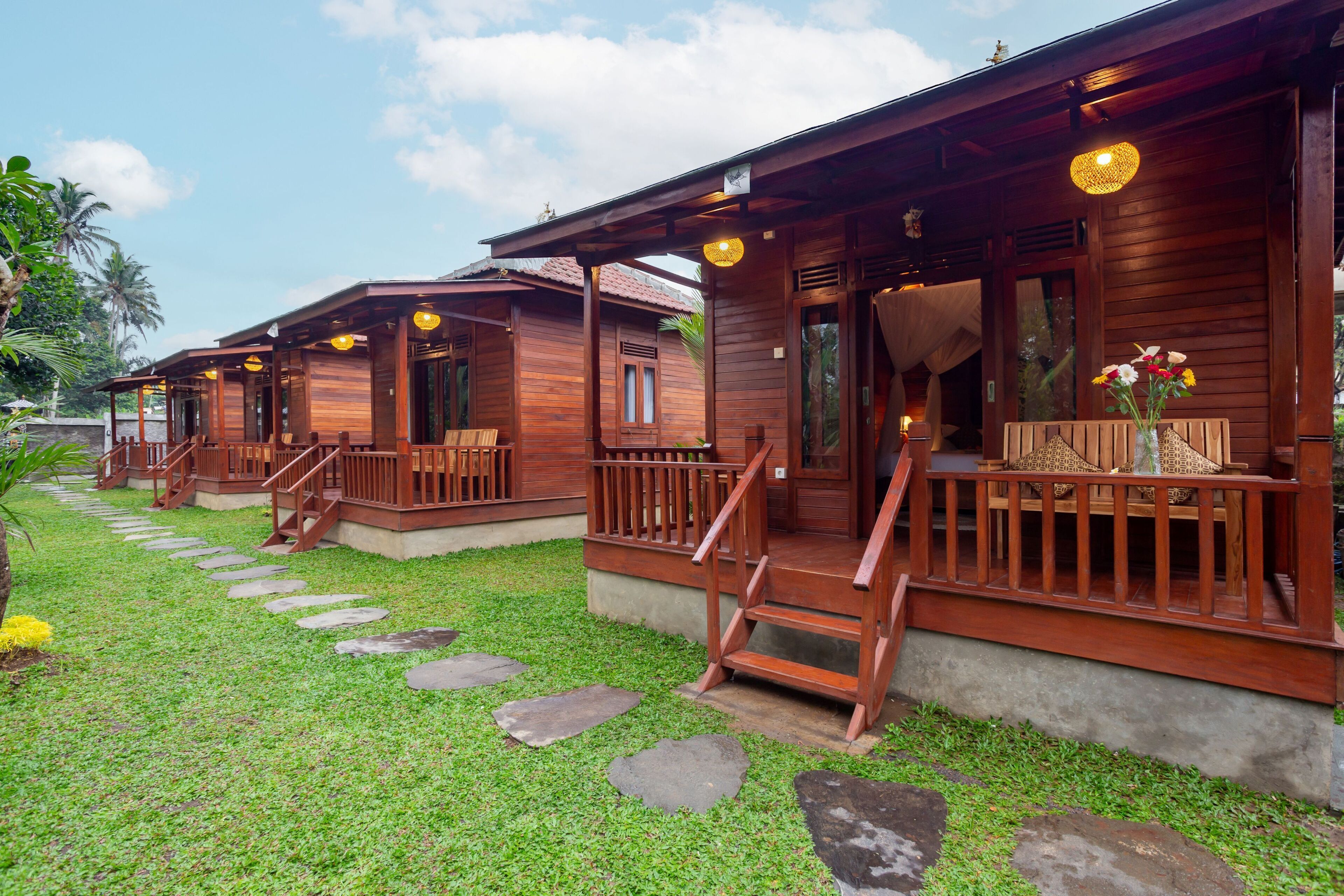 A row of wooden cabins with wooden railings and steps leading to the entrance.
