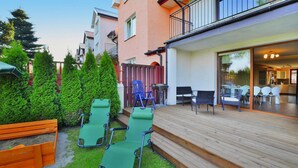 Une terrasse avec coin salon extérieur, une terrasse en bois et une vue sur l’immeuble voisin.