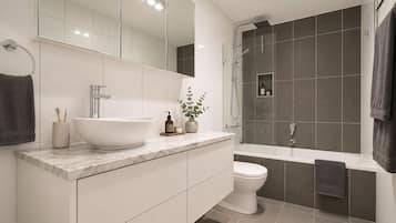 A modern bathroom with a large white sink, a toilet, a shower area, and a mirror above the sink.