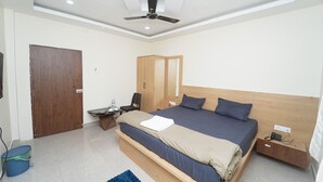 A modern bedroom with a bed, wooden wardrobe, desk, chair, and a ceiling fan. - Deepak Resort (Chatabar)
