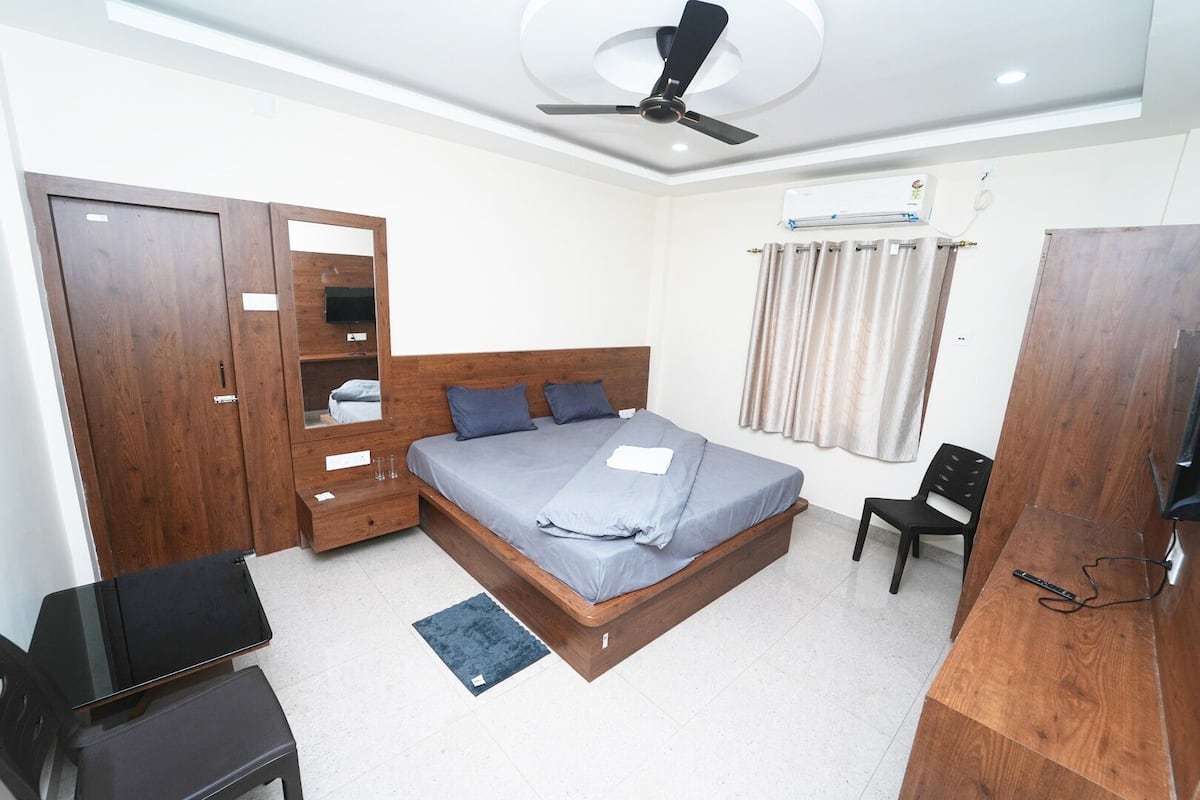 Une chambre moderne avec un lit en bois, une armoire, un bureau et un ventilateur de plafond.