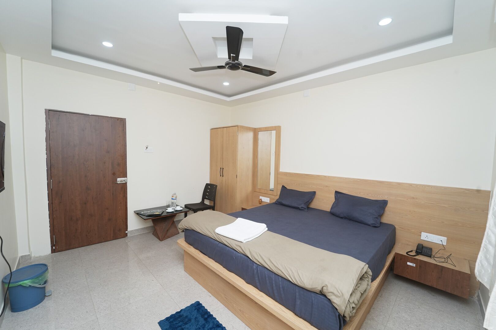 Una camera da letto moderna con un letto, una scrivania, una sedia, un armadio e una ventola a soffitto.