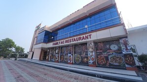 A two-story building with a sign reading "Family AC Restaurant" and large posters of food items on the windows. - Deepak Resort (Chatabar)