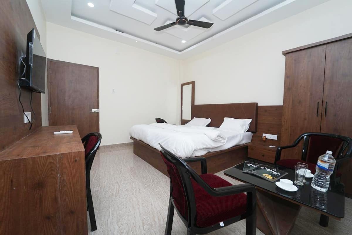 Une chambre d’hôtel équipée d’un lit, d’un bureau, d’une chaise, d’une table, d’une bouteille d’eau et d’un téléviseur.