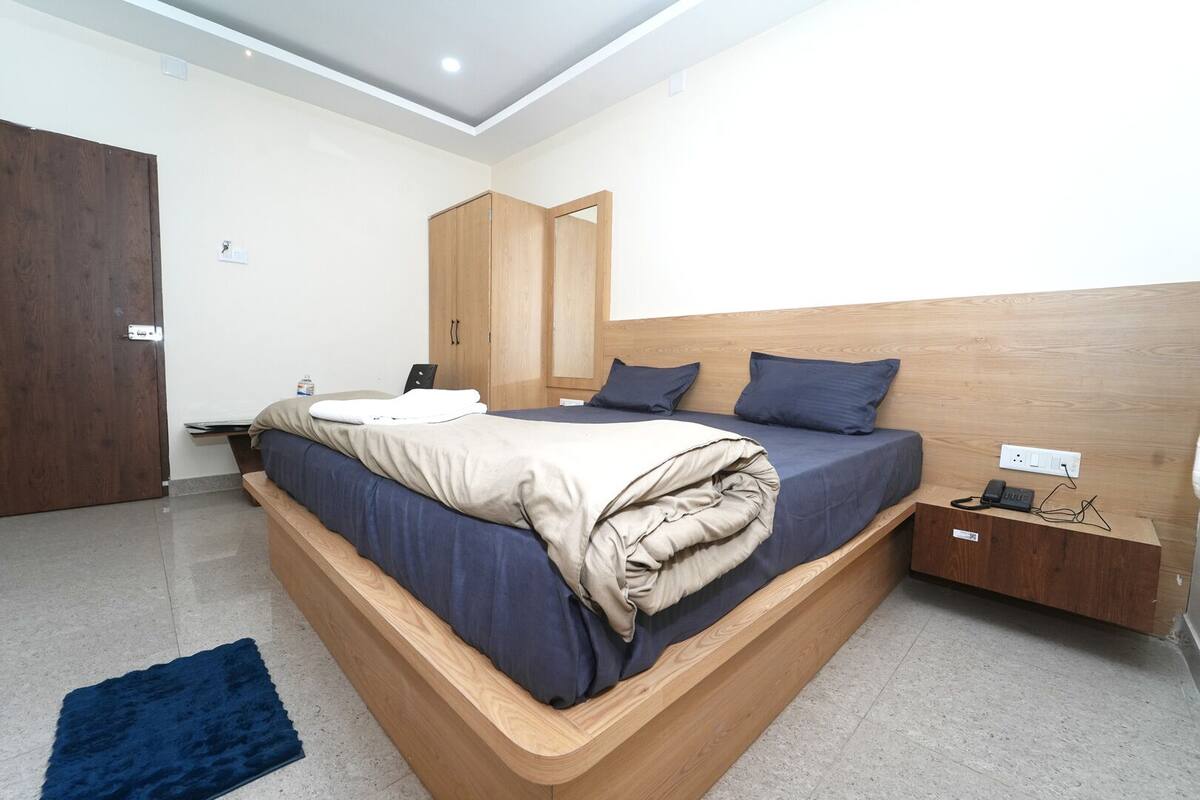Une chambre moderne avec un lit en bois, un banc intégré, une armoire et une table de chevet avec un téléphone.