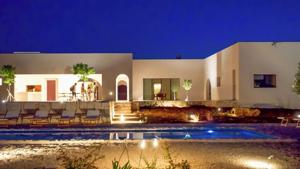 Un edificio moderno con piscina, area relax all'aperto e ingresso ben illuminato.