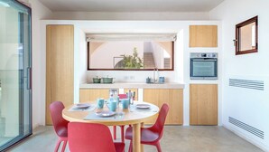 Una cucina compatta con zona pranzo, inclusa una tavola rotonda con sedie, una finestra con vista su una scala e elettrodomestici integrati.