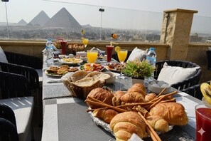 A table set with food and drinks, overlooking a cityscape with pyramids. - eco home suite (Giza)